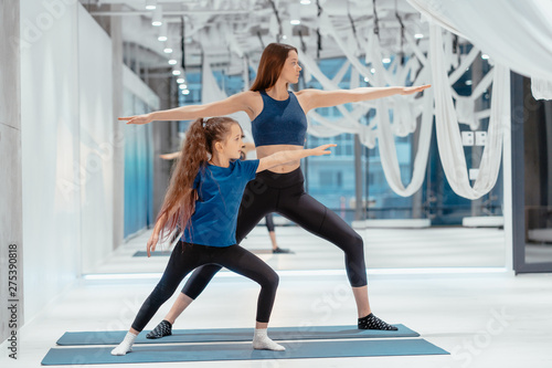 Young adult mom and little daughter together on aerobics