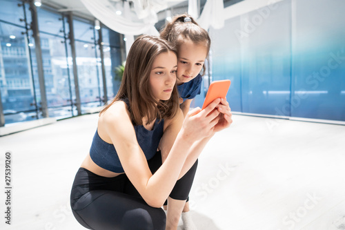 mother and girl using phone in gym for watching video © teksomolika