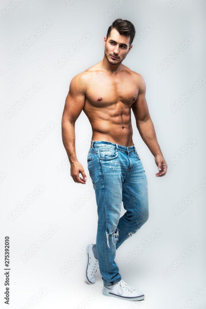 Male model with perfect body in jeans posing over grey background.  Close-up. Studio shot. Stock Photo | Adobe Stock