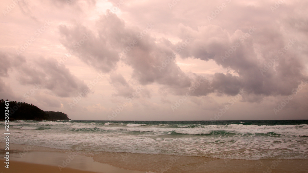 Sunset on Karon beach. Heavy clouds over the sea. The surf pounds the shore. Phuket, Thailand