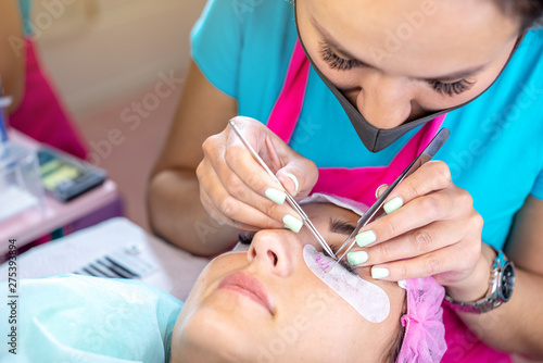 Woman master in the beauty salon work on eyelash extension to the client. Concept of profession in the field of beauty services