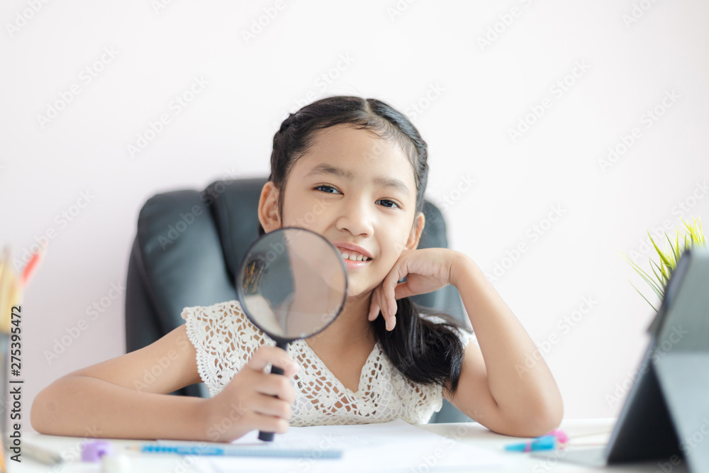 Little Asian girl using magnifier doing homework and smile with happiness for education concept select focus shallow depth of field Little Asian girl using magnifier doing homework and smile with happiness for education concept select focus shallow depth of field