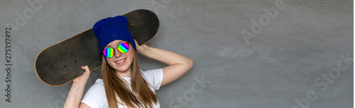 Teenager girl in sunglasses and hipster millennial hat with skateboard near the colorful wall, generation leisure concept photo