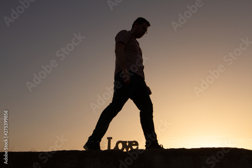 silhouette of man with poster that puts love