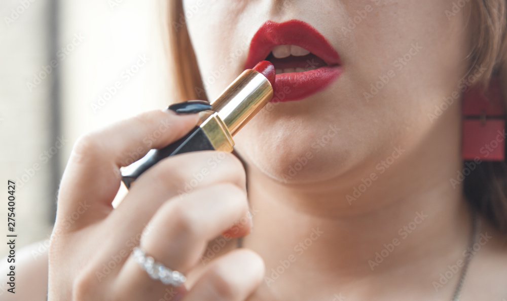 Beautiful and stylish woman applying lipstick.