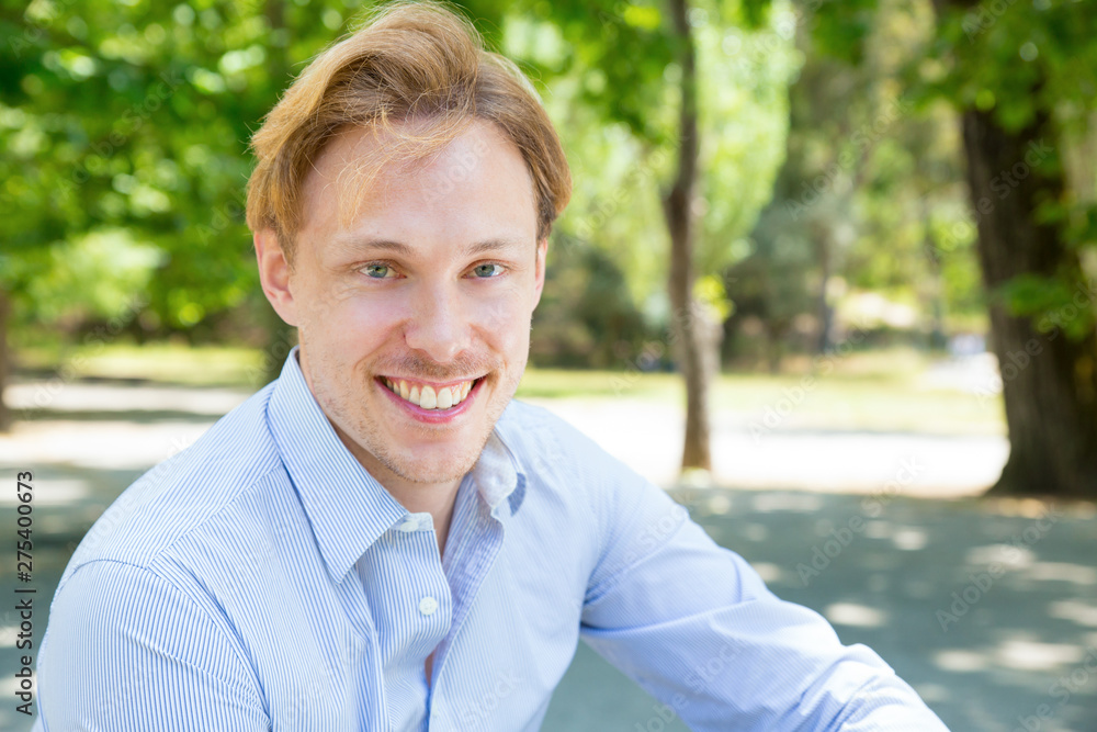 Happy joyful guy enjoying leisure time outdoors. Headshot of handsome young man looking at camera and smiling. Handsome man portrait concept Happy joyful guy enjoying leisure time outdoors. Headshot of handsome young man looking at camera and smiling. Handsome man portrait concept