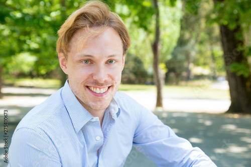 Happy joyful guy enjoying leisure time outdoors. Headshot of handsome young man looking at camera and smiling. Handsome man portrait concept