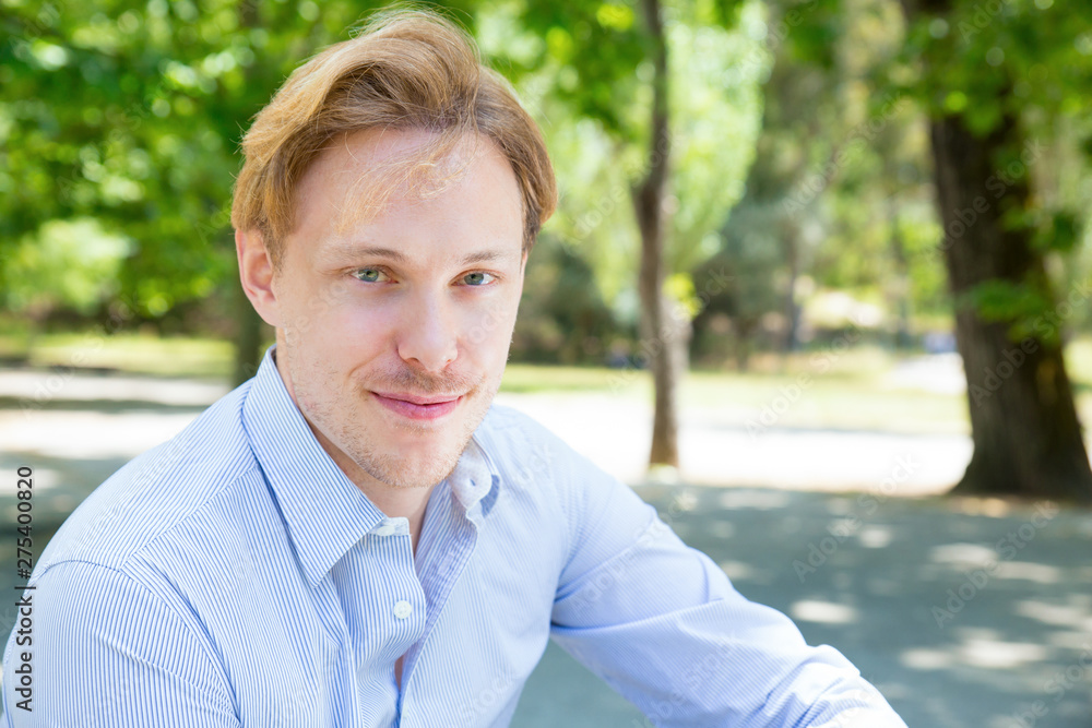 Joyful attractive guy posing in park. Closeup of young man looking at camera and smiling. Handsome man concept Joyful attractive guy posing in park. Closeup of young man looking at camera and smiling. Handsome man concept