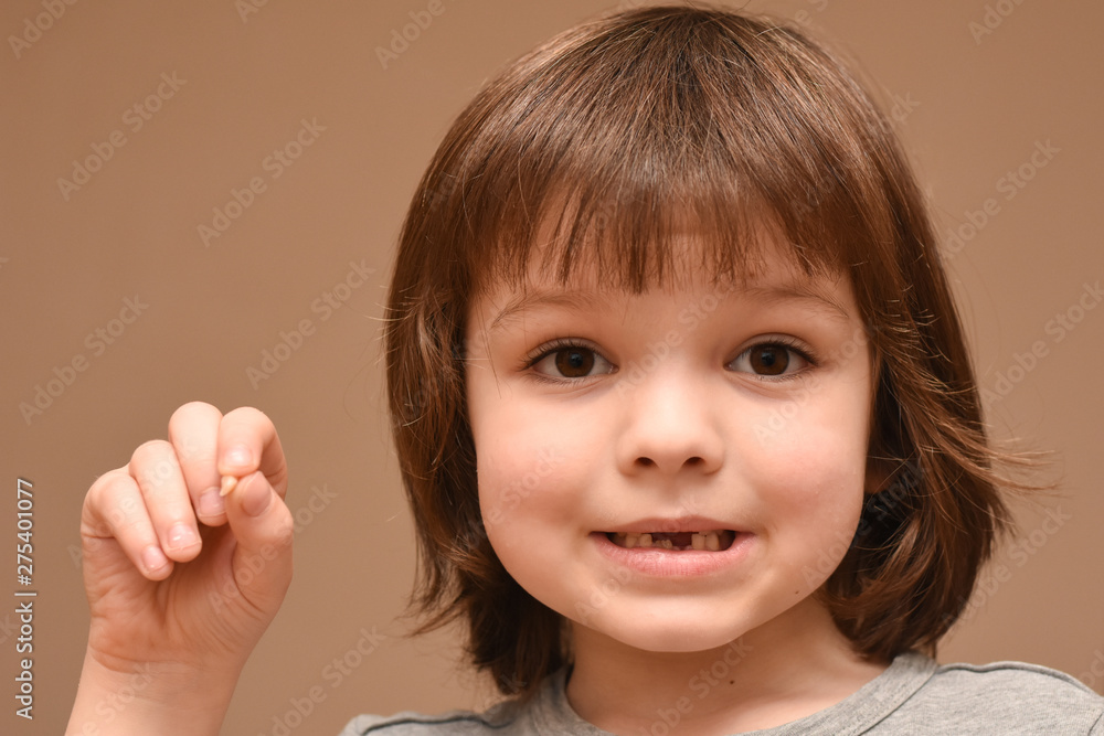 Happy boy smiling and showing his milktooth that has fallen out. Child