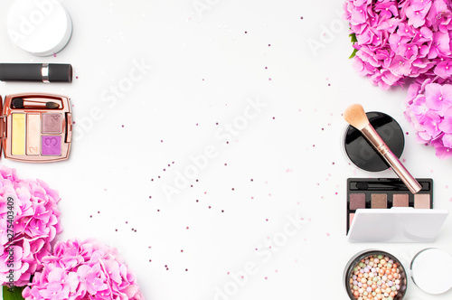 Set of decorative cosmetics mascara powder lipstick eyeshadow blush makeup brush pink hydrangea flowers star confetti on light background top view Flat lay. Beauty blogger concept. Fashion background