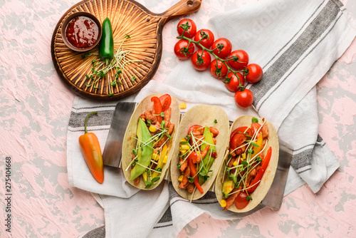 Tasty fresh tacos on color background