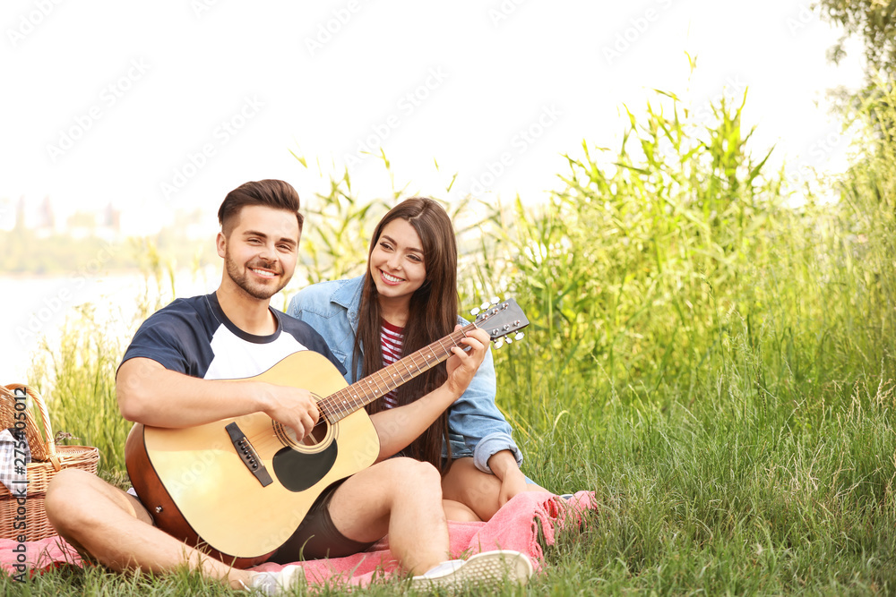 Young couple with guitar on picnic in park Young couple with guitar on picnic in park