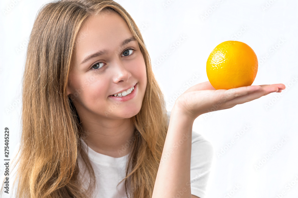 Beautiful smiling girl with long hair in a white shirt holding orange isolated on white background