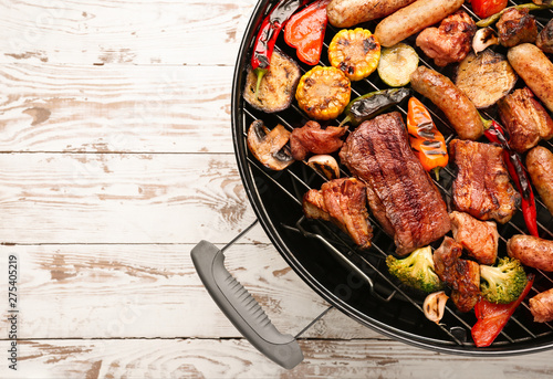 Grill with tasty cooked meat and vegetables on wooden background