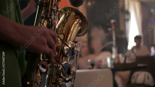 Musician play saxophone on background blurred silhouettes people at party