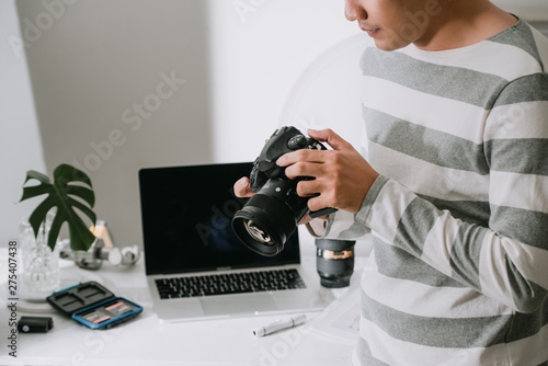 male photographer holding digital camera above the desk in his photo studio