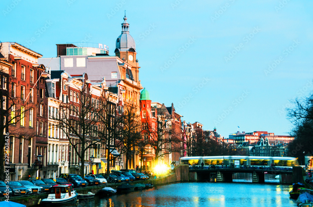 Illuminated bridge and historical buildings in Amsterdam, Netherlands at night