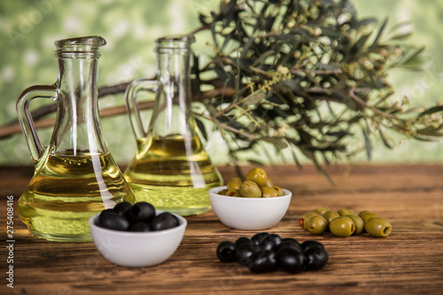 Olive oil, olive tree and green and black olives on a wooden table