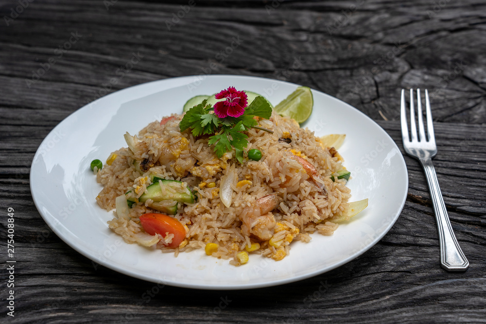 Fried rice with shrimps and vegetables in a white dish on an old wooden table, close up . Thai food , Thai cuisine Fried rice with shrimps and vegetables in a white dish on an old wooden table, close up . Thai food , Thai cuisine