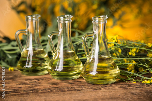 Rapeseed flowers and rapeseed oil in a bottle on the table