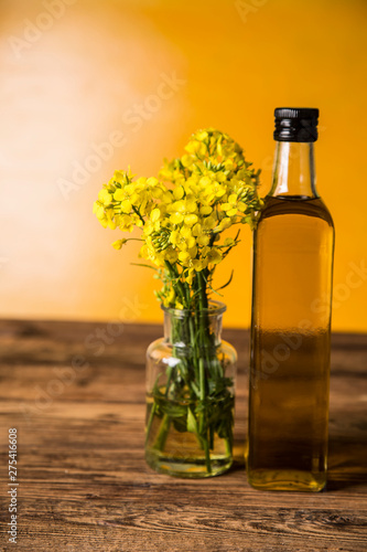 Rapeseed flowers and rapeseed oil in a bottle on the table