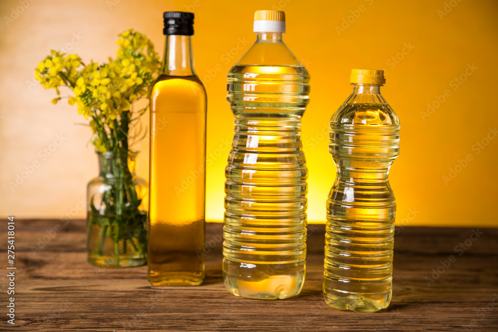 Rapeseed flowers and rapeseed oil in a bottle on the table Rapeseed flowers and rapeseed oil in a bottle on the table