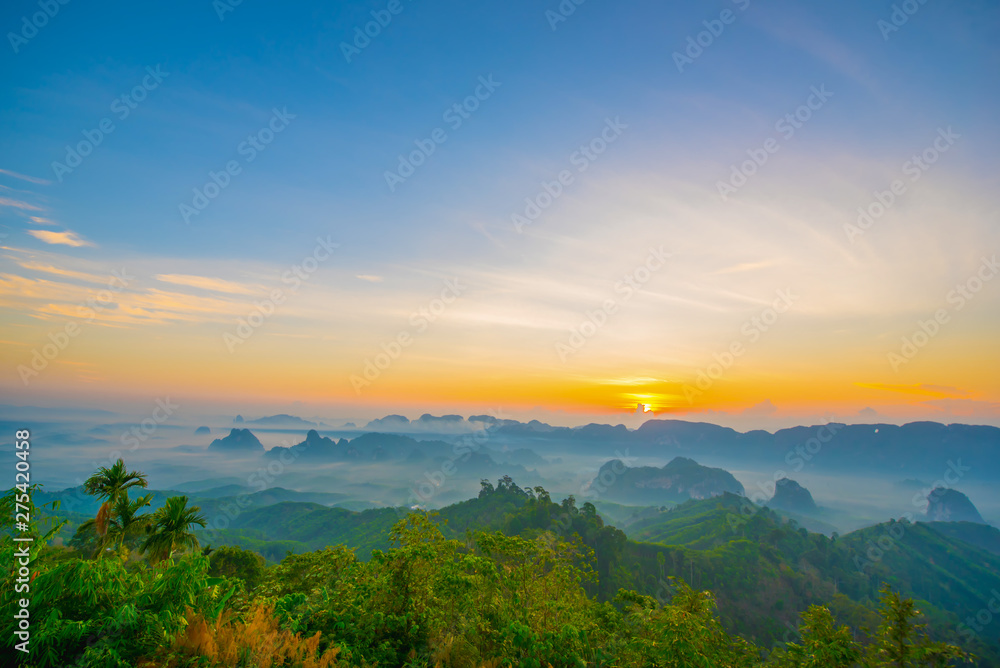 Beautiful mountain range with sky blue and orange light of the sun through the clouds in the sky, Background sky during Sunrise with fog on mountain, Abundant lush forest-Image