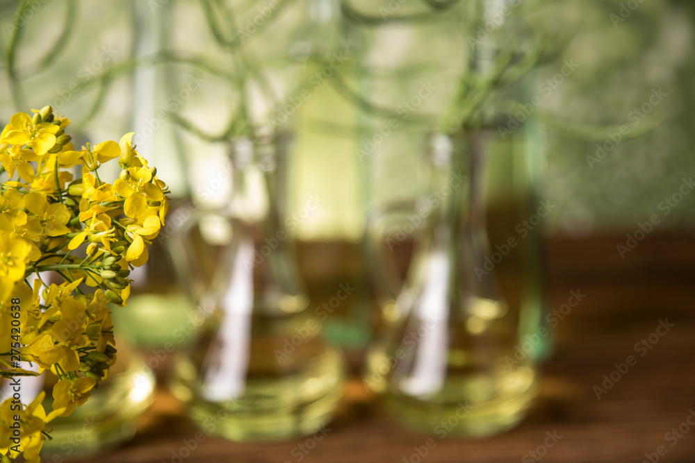 Seeds and rape flowers in bottles and carafes with rapeseed oil