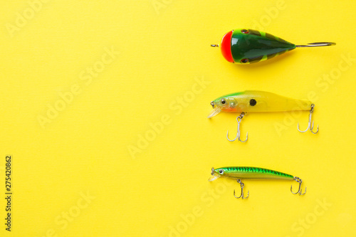 Fishing hooks and baits in a set for catching different fish on a yellow background with copy space. Flat lay