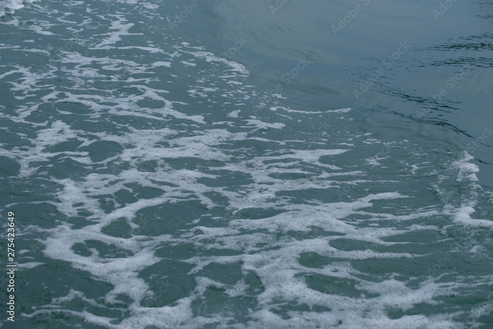 Trail on the water from the boat, sea waves bubble foam from boat. Stock photo image of ocean waves and sea foam caused by the sail of a speed boat, water surface behind of fast moving motor boat