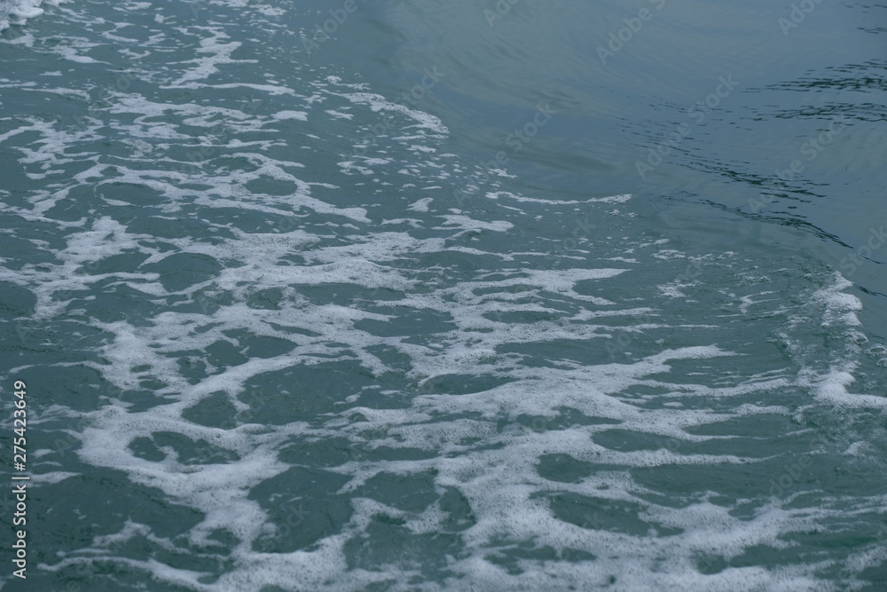 Trail on the water from the boat, sea waves bubble foam from boat. Stock photo image of ocean waves and sea foam caused by the sail of a speed boat, water surface behind of fast moving motor boat Trail on the water from the boat, sea waves bubble foam from boat. Stock photo image of ocean waves and sea foam caused by the sail of a speed boat, water surface behind of fast moving motor boat