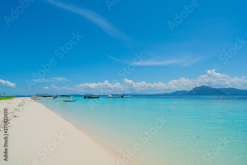 White coral sand beach with moored line-up of boats used to bring tourists to island with moored line-up of boats used to bring tourists to island