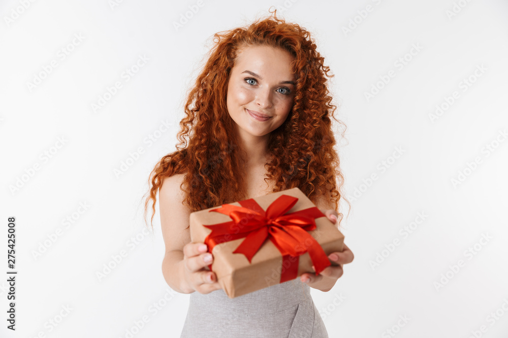 Redhead curly girl isolated over white wall background holding surprise box gift.