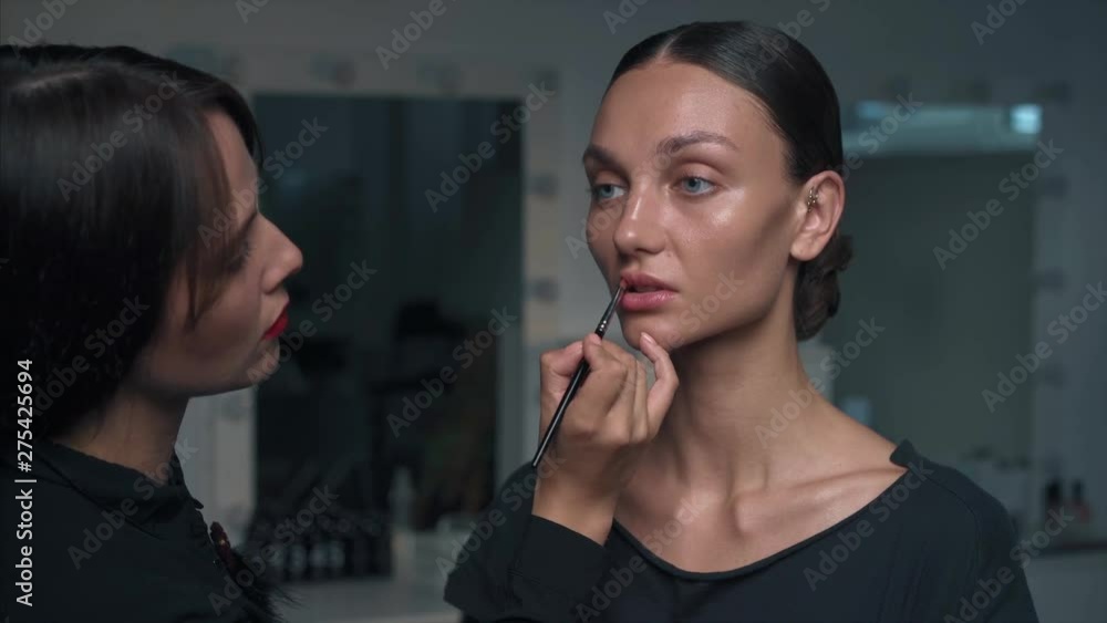 Makeup artist paints lips of a Beautiful model Makeup artist paints lips of a Beautiful model