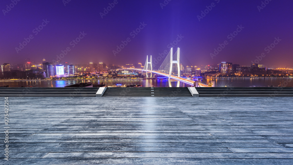 Empty wooden board square and bridge buildings at night in Shanghai,China