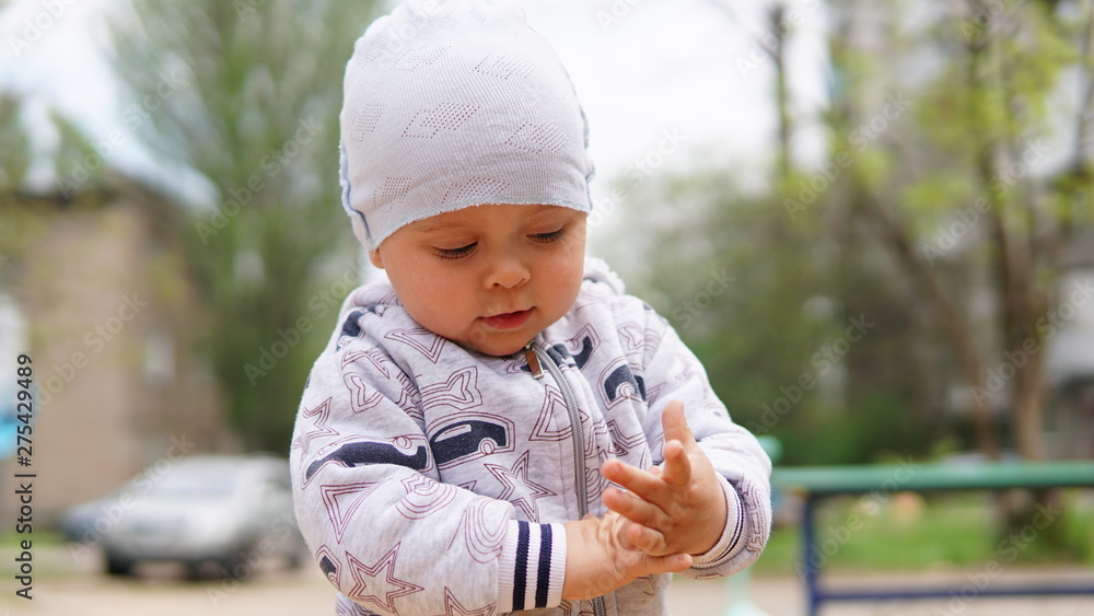 Adorable toddler in the white hat outdoor on the playground Adorable toddler in the white hat outdoor on the playground