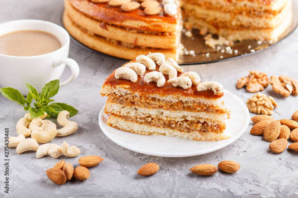 Piece of homemade cake with caramel cream and nuts with cup of coffee on a gray concrete background, side view. Piece of homemade cake with caramel cream and nuts with cup of coffee on a gray concrete background, side view.