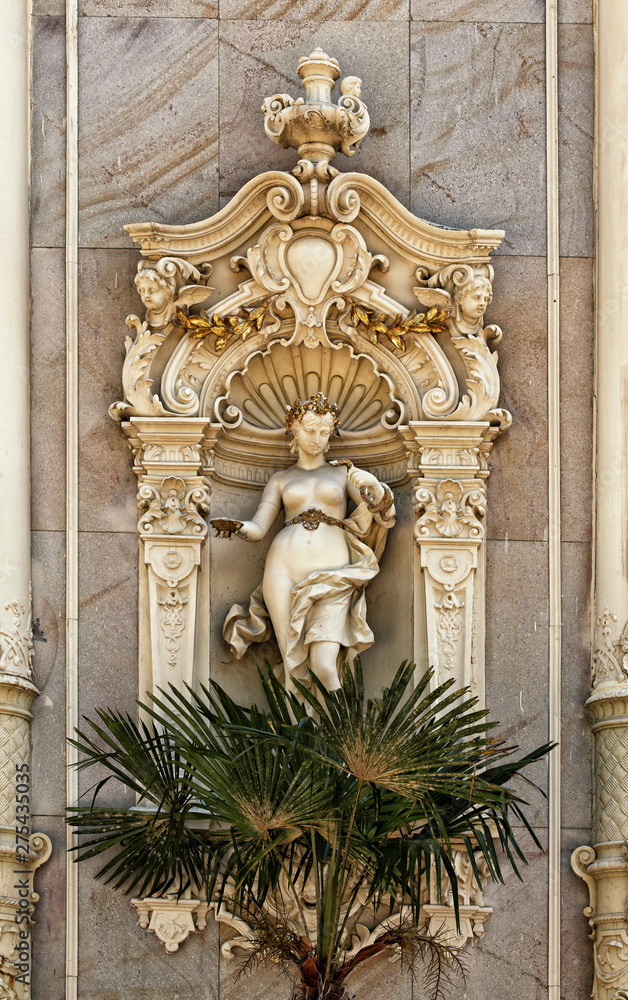 Statue of the young naked lady over the palm