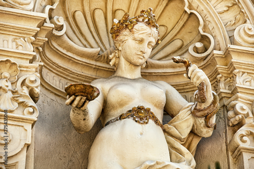 Statue of naked lay holding snake and saucer