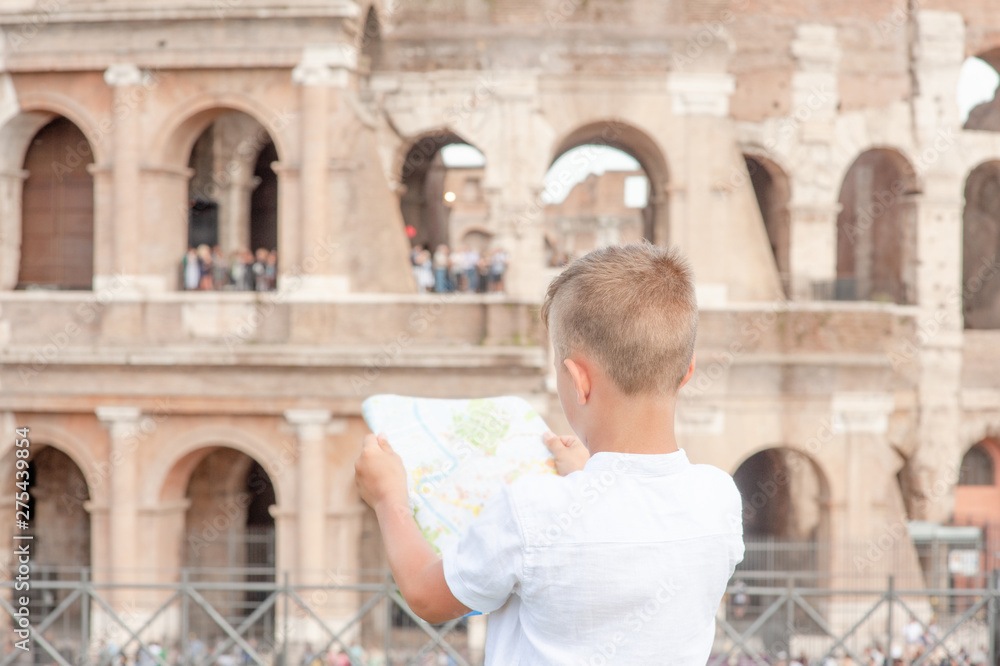 Little boy looking at tourist map in Rome in front of Colosseum, Italy. Back view, Empty space for text