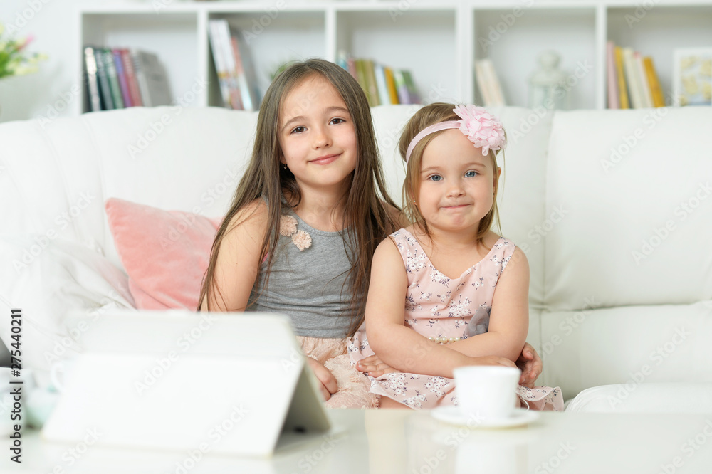 Portrait of two cute little girls sitting on sofa Portrait of two cute little girls sitting on sofa