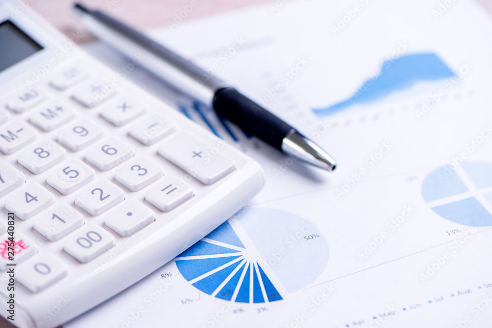 White calculator and report with chart and graph, concept of annual financial profit overview, banking and investment, copy space, macro, close up White calculator and report with chart and graph, concept of annual financial profit overview, banking and investment, copy space, macro, close up