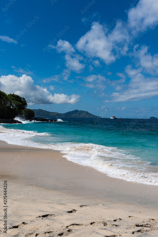 View of tropical beach, sea rocks and turquoise ocean, blue sky. White Sand Beach, Bali Indonesia.