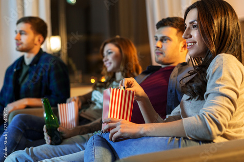 friendship and leisure concept - friends with beer and popcorn watching tv at home at night