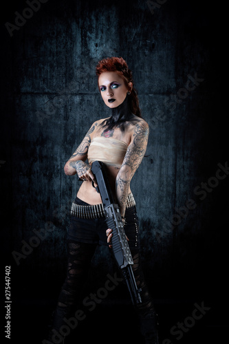 Young tattooed woman, one-eyed, rifle in his hands photo