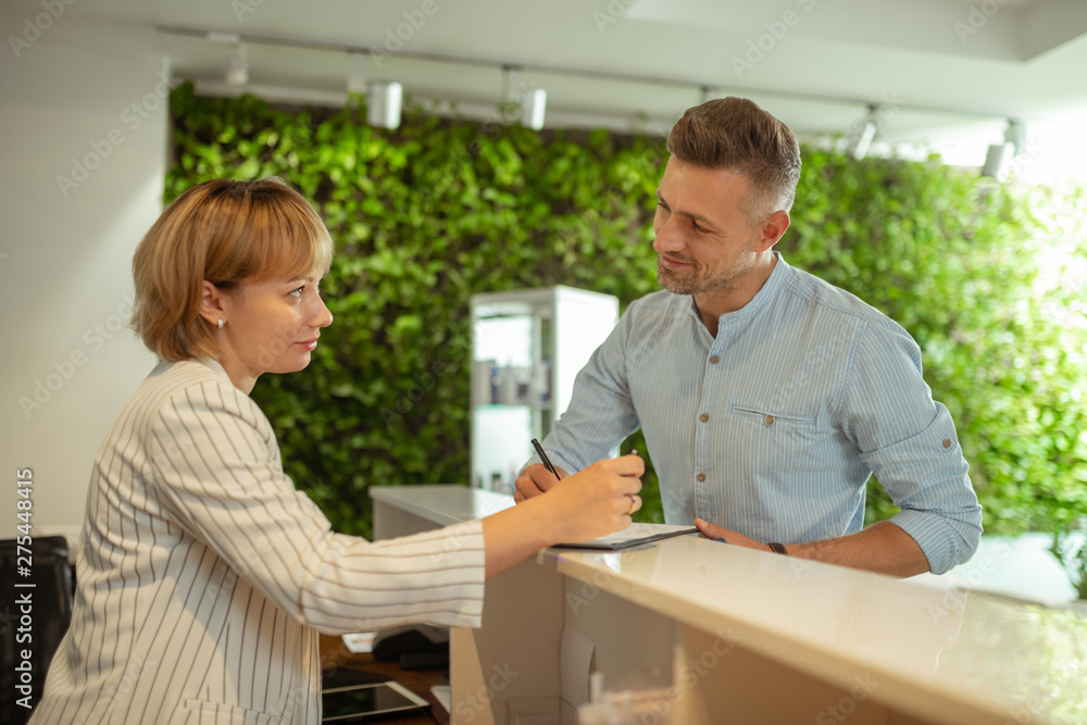 Administrator wearing striped jacket talking to constant client Administrator wearing striped jacket talking to constant client
