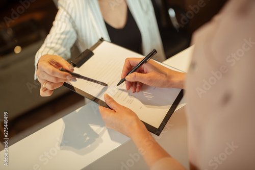 Woman holding pen while writing personal details in clinic