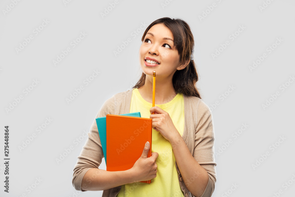 education, high school and knowledge concept - asian student woman with books and pencil over grey background education, high school and knowledge concept - asian student woman with books and pencil over grey background