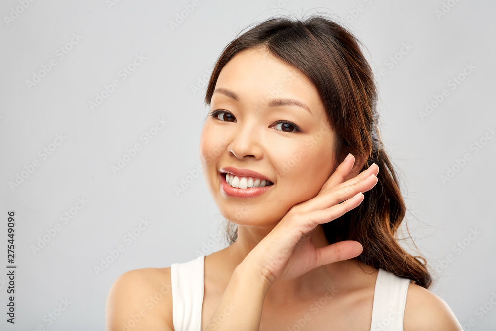 beauty and people concept - happy smiling young asian woman touching her face beauty and people concept - happy smiling young asian woman touching her face