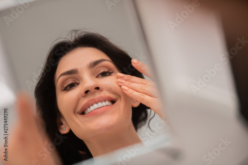 Satisfied woman touching her face after plastic surgery photo